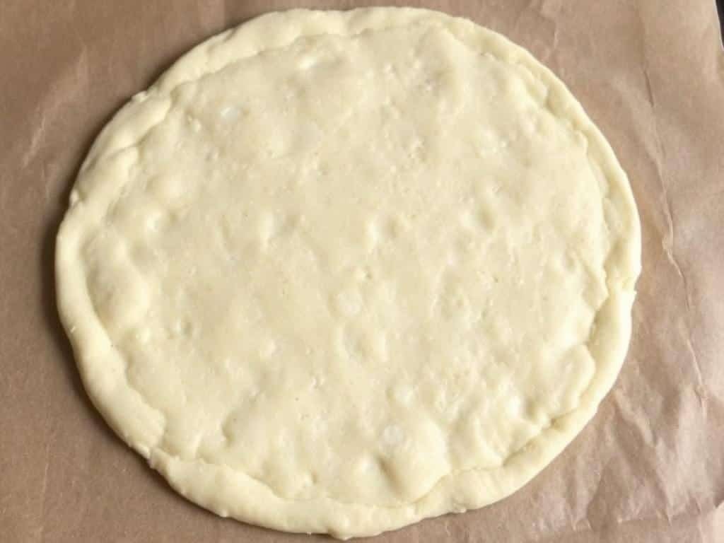 Par-baked gluten free pizza crust showing light browning