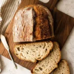 Loaf of freshly baked homemade sourdough bread on a wooden table