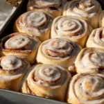 Delicious homemade cinnamon rolls topped with creamy icing on a wooden table.