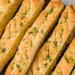 Freshly baked gluten-free garlic breadsticks served with marinara sauce.
